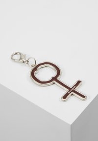 Přívěsek na klíče ve tvaru ženského symbolu, s burgundským smaltovým designem a kovovými okraji a stříbrným klipem.