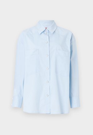 Lys blå skjorte med lange ermer, to frontlommer og krage. Har en ensfarget tekstur og knappeåpninger ved mansjettene.