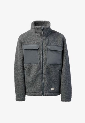 Giacca in pile grigio scuro con collo alto, zip frontale, due grandi tasche sul petto con patta e tasche laterali, tessuto morbido e strutturato.