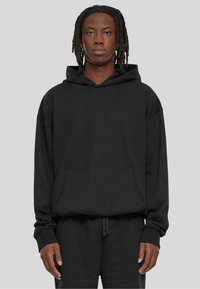 Sudadera negra hecha de tela suave, con un gran bolsillo frontal, capucha con cuerda y un corte holgado con puños y dobladillo acanalados.