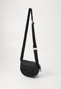 Black crossbody bag with a rounded shape, made of fabric featuring mesh detailing, adjustable strap, and silver hardware accents.