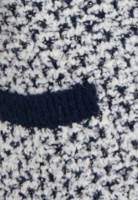 Tessuto a maglia con un motivo testurizzato in blu navy e crema, con riflessi metallici dorati. Una striscia solida blu navy corre orizzontalmente.