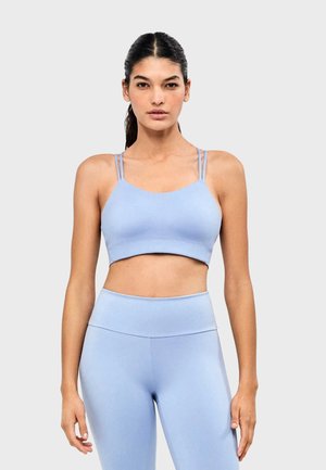 Sujetador deportivo azul claro hecho de material elástico, con tirantes dobles finos, diseño cropped y textura suave.