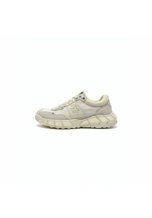 Beige lage sneaker met dikke, gestructureerde zool, vetersluiting en subtiel logo aan de zijkant, gezien vanuit lateraal perspectief op een witte achtergrond.