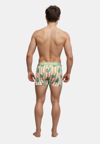Herre boxer briefs med et mønster af grønne avocadoer på en stribet orange baggrund, med en lys blå elastik der har teksten "MR. KO".