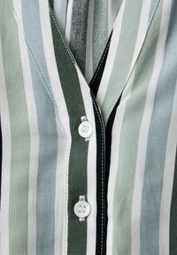 Chemise à rayures verticales avec des rayures alternées vertes, bleu clair, blanches et noires, comprenant deux boutons blancs sur la patte de boutonnage.
