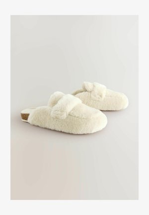 Cremefarbene Hausschuhe aus weichem, flauschigem Material mit einer strukturierten Oberfläche, ausgestattet mit einem Riemen über dem Spann und einer flachen Sohle.