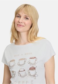 Hvid kortærmet t-shirt med trykte kaffekopper og teksten "HAVE A GOOD COFFEE." Blødt stof med en afslappet pasform.