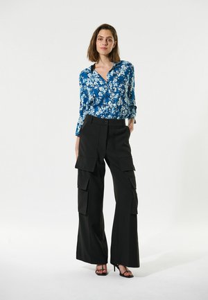Blaue Blumen-Hemd mit Knöpfen, kombiniert mit hochtaillierten schwarzen Cargo-Hosen mit Taschen. Das Outfit hat eine lässige Passform und ein vielseitiges Design.