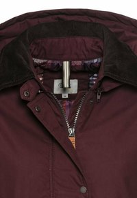 Weinrote Jacke mit einem Cordkragen, Reißverschluss und Druckknöpfen. Das Innenfutter hat ein gemustertes Design und eine Aufhängeschlaufe. Größenetikett sichtbar.