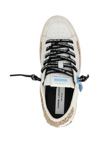 Sneaker in pelle bianca con accenti dorati glitterati, lacci neri con testo bianco e punta perforata per la ventilazione. Etichetta del brand visibile all'interno.