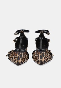 Tacones con estampado de leopardo, correas de cuero negro y herrajes dorados. Diseño de punta redonda y correa en el tobillo, con un cuerpo de tejido texturizado.