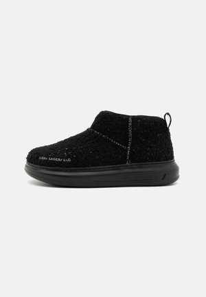 Schwarze Knöchelstiefel mit einem Obermaterial aus strukturiertem Stoff, das ein schnürsenkelloses Design, einen Zugriemen und eine dicke schwarze Gummisohle aufweist.