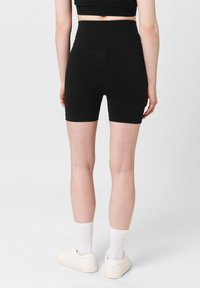 Czarne wysoka talia szorty rowerowe wykonane z elastycznego materiału, charakteryzujące się gładką teksturą i dopasowanym krojem, kończące się powyżej połowy uda.