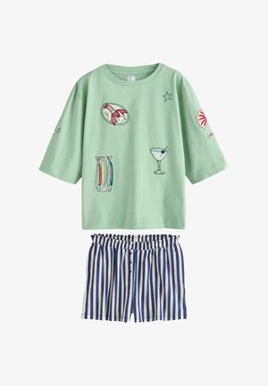 Hellgrünes, übergroßes Hemd mit Stickerei von Meeresfrüchten und Cocktails, kombiniert mit blau-weiß gestreiften Shorts mit senkrechten Streifen und Knöpfen.