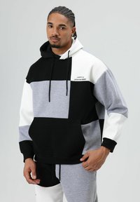 Hooded sweatshirt featuring a color-block design in black, grey, and white, made from a soft material with a front pocket and drawstrings.