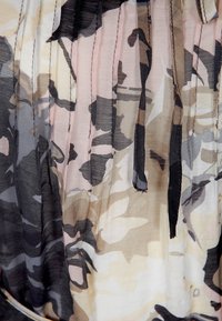 Blusa stampata con un tessuto morbido e trasparente che presenta un motivo camouflage in tonalità di beige, grigio e rosa pastello. Include dettagli plissettati.