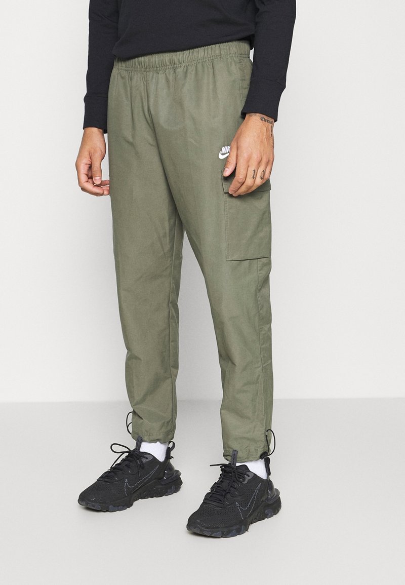 Lätta olivgröna cargobyxor med elastisk midja, elastiska muddar och en sidoficka. I kombination med svarta sneakers och vita strumpor.