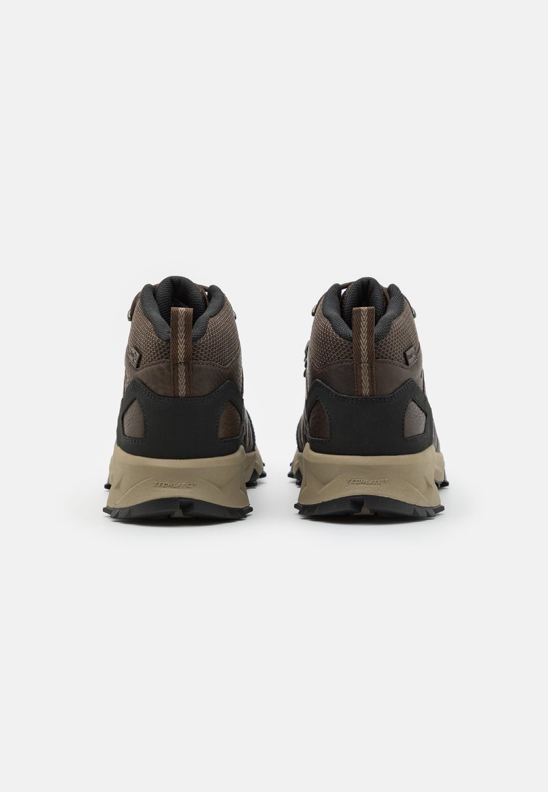 Zapatos de senderismo en marrón y negro con una parte superior de malla texturizada, talón reforzado y suela de goma diseñada para tracción.