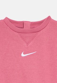 Ροζ φούτερ με υφή και ribbed λαιμόκοψη. Διαθέτει μικρό λευκό λογότυπο Nike στο στήθος, με απαλή υφή.