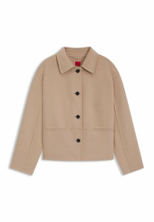 Giacca cropped in misto lana beige con colletto, sei bottoni neri e cuciture orizzontali. Caratterizzata da maniche lunghe e design minimale.