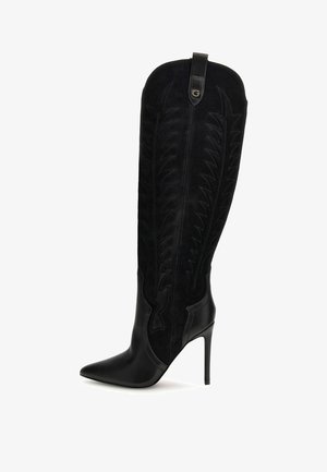 Bottes à talons hauts noires avec une tige en suède ornée de motifs de feuilles en relief, bout pointu et une touche de cuir lisse sur le talon inférieur.