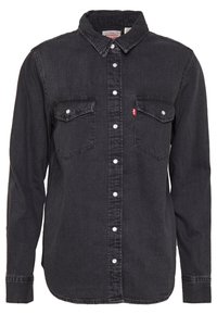 Camicia in denim nera con maniche lunghe, colletto a bottoni, due tasche sul petto e bottoni bianchi. Presenta una leggera texture e un dettaglio del logo Levi's.