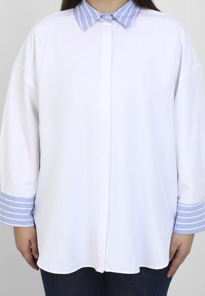Chemise blanche avec un col et des poignets rayés bleu clair. Fabriquée en tissu lisse, elle présente un devant à boutons et de longues manches amples.