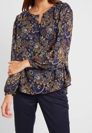 Marinebluse mit einem floralem und paisleymuster in Gelb und Weiß. Verfügt über einen V-Ausschnitt und geraffte lange Ärmel, aus leichtem Stoff gefertigt.
