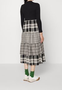 Top negro de canalé y una falda con volantes en tejidos de espiga en blanco y negro. Combinado con zapatillas blancas y calcetines verdes.