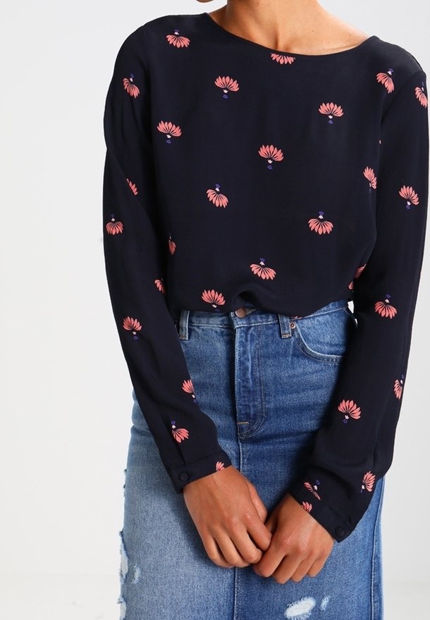 Marinblus med långa ärmar, med rosa blommönster. Matchas med en slitna denimkjol för en lager-på-lager-look.
