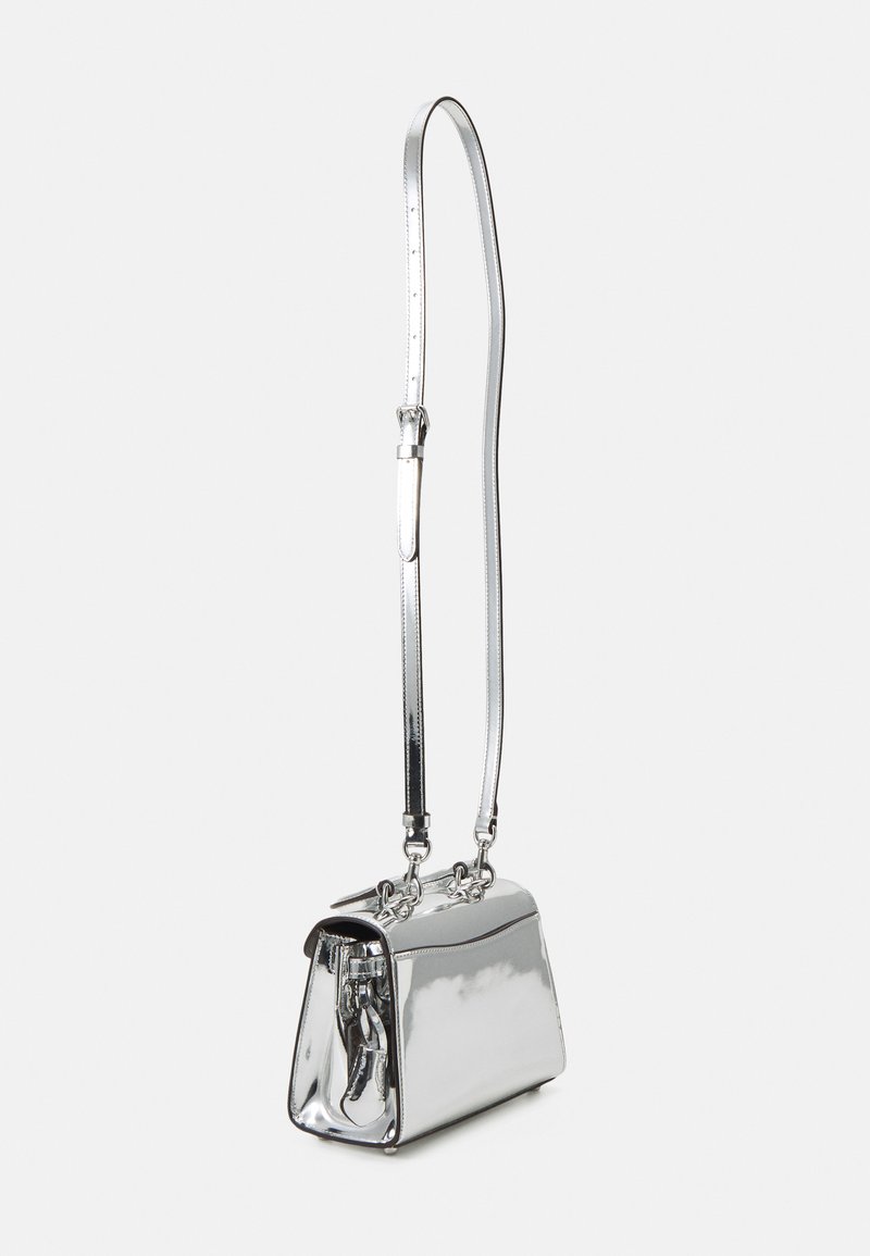 Sac de bandoulière en métal argenté avec une forme structurée, fermeture zippée sur le dessus et une bandoulière ajustable ; il est orné d'accents en chaîne et a une finition brillante.