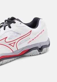 White and gray athletic shoe with black laces, red accents, and "Wave Phantom 3" text on the side, showing sole and mesh details.
