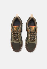 Scarpe sportive verdi in materiali mesh e suede. Le caratteristiche includono dettagli arancioni, lacci beige e una suola in gomma texture.