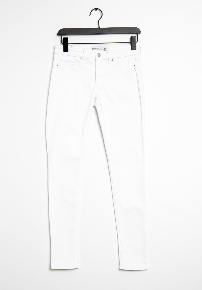 White cotton skinny jeans displayed on a black hanger. Features include a front button closure, five pockets, and narrow leg design.