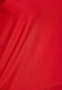 Kirkas punainen kangas, jossa on sileä pinta ja hienovarainen kiilto. Materiaalissa on hienoa vaakasuoraa raidoitusta ja tasainen väri koko alueella.