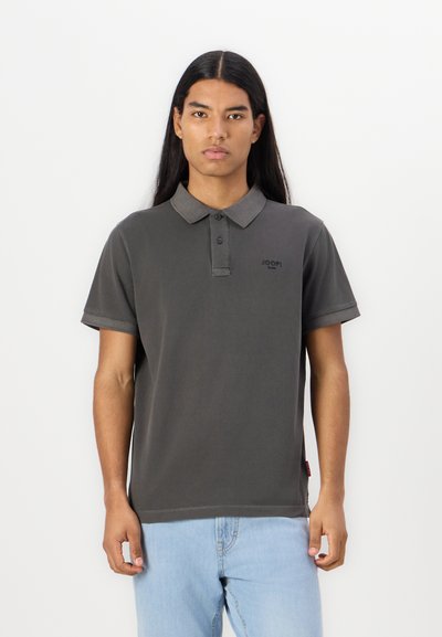 Polo noir foncé avec un col à trois boutons, des manches courtes et un logo discret sur la poitrine. Matière en coton lisse.