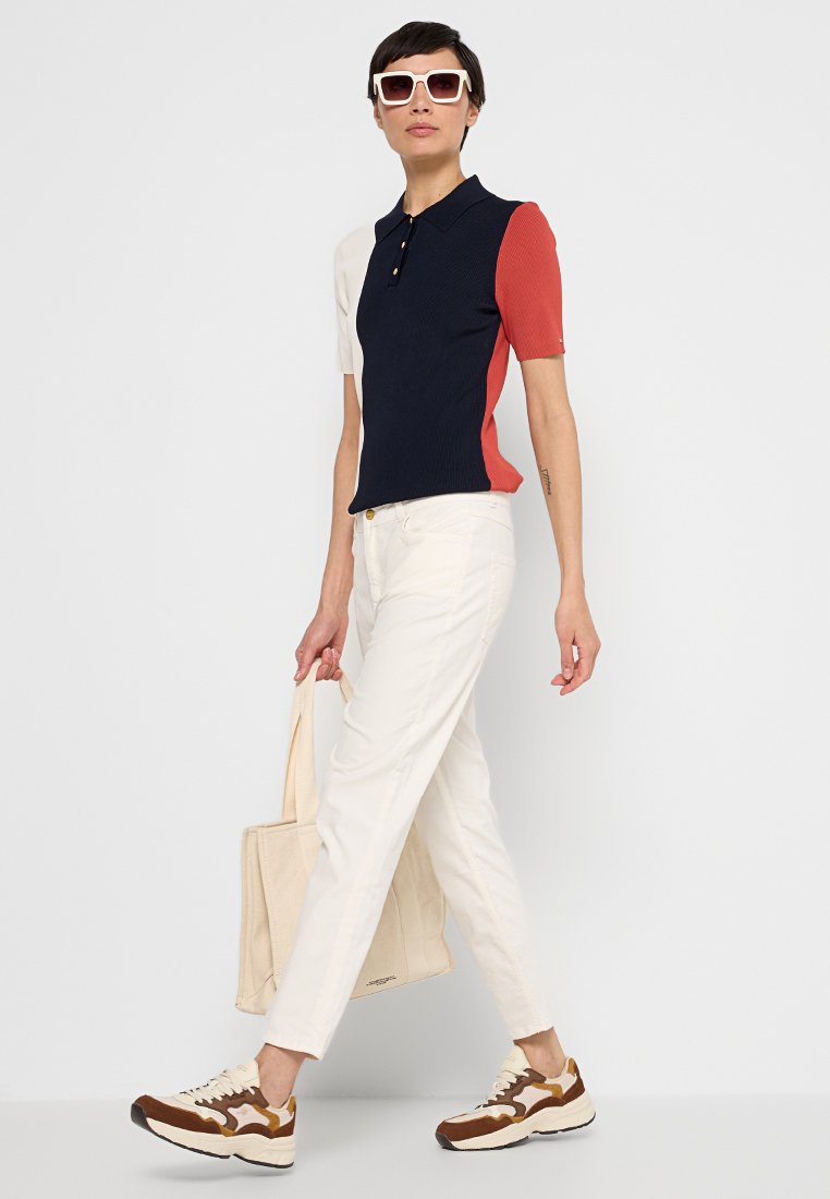 Polówki w kolorach granatowym, białym i czerwonym, z żebrową strukturą, połączone z białymi spodniami i brązowymi trampkami. W zestawie torba płócienna.