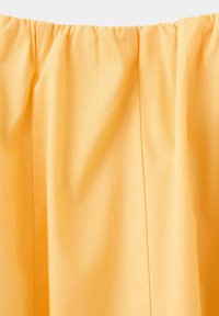 Jupe en tissu jaune avec une ceinture élastique froncée et des coutures verticales visibles.