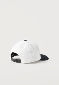 Άσπρο καπέλο baseball από κορδούρα με μαύρο ρυθμιζόμενο λουρί snapback και μαύρο κυρτό γείσο, εμφανίζεται από πίσω σε λευκό φόντο.