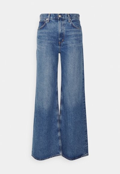 Vide beneduser med høy midje i lys blå denim. Har frynsekanter og klassisk fem-lommers stil. Glatt tekstur.