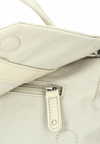 Beige stoffen tas binnenzijde met textuur; voorzien van een rits, leren handvat en stiksels.