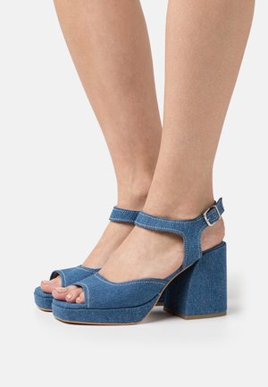 Denim platform sandalen met open tenen, blauwe stof, enkelbandje en dikke hakken. Voorzien van witte stiksels en een gladde textuur.