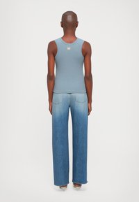 Light blue ribbed tank top with a rounded neckline and a logo tag, paired with wide-leg jeans featuring a gradient from light to dark denim.