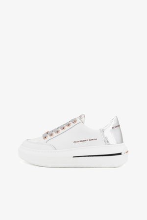 Sneaker bianco con lacci grigi e occhielli in oro rosa. Presenta un accento argentato lucido sul tallone e una suola bianca spessa con dettagli neri.