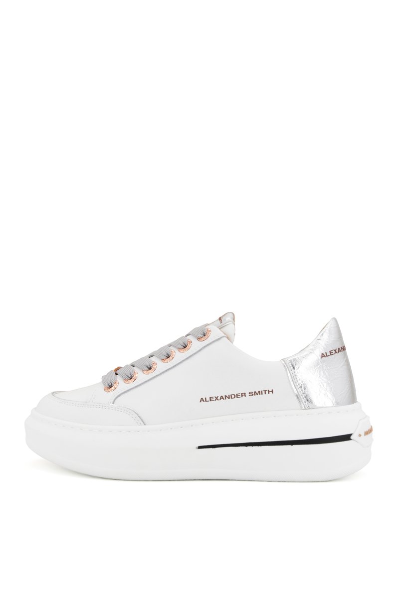 Sneaker bianco con lacci grigi e occhielli in oro rosa. Presenta un accento argentato lucido sul tallone e una suola bianca spessa con dettagli neri.