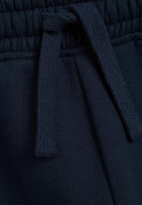 Marinblå sweatpants med en texturerad elastisk midjeband och en knytbar snörning, tillverkade av mjukt tyg med en slät yta.
