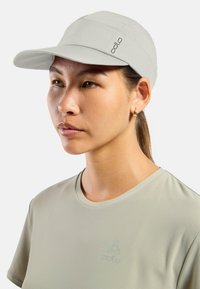 Light gray cap with a stiff brim, made of smooth fabric. Features a logo on the side and a fitted design. Worn with a matching gray shirt.