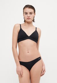 Zwarte bikini-set met een driehoekige bralette met dunne bandjes en een bijpassende low-rise onderkant. Gladde stof met minimale stikdetails.