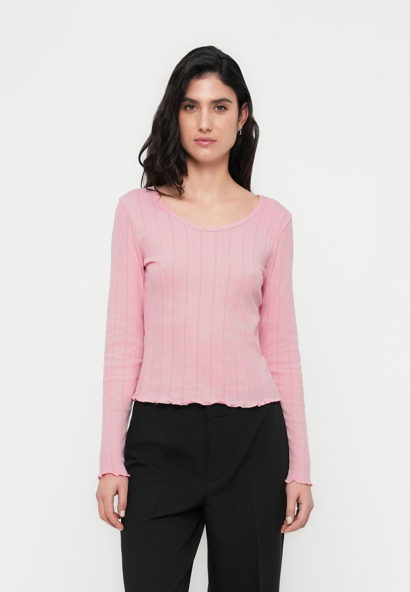 Μπλούζα με μακριά μανίκια, ριμπ ύφανση σε ανοιχτό ροζ χρώμα, με φαρδιά λαιμόκοψη, σκαλωτό τελείωμα και εφαρμοστή γραμμή, σε συνδυασμό με σκούρο παντελόνι.